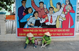 Can Tho Street Cleaners resting against poster